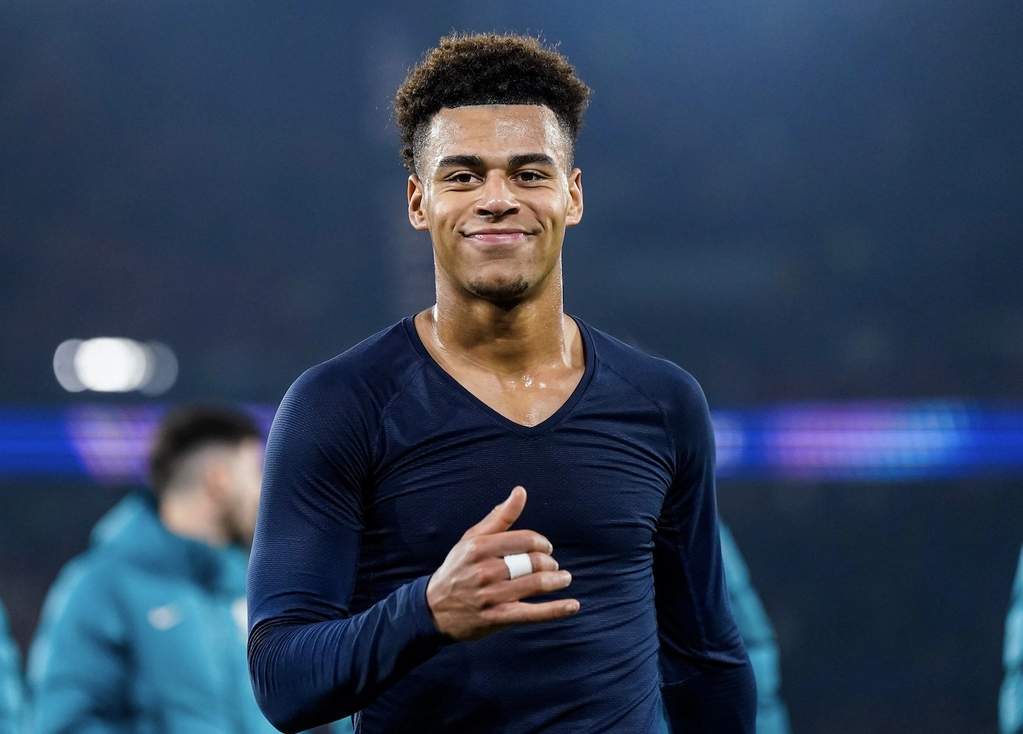 Desire Doue smiling while holding a signed football jersey.